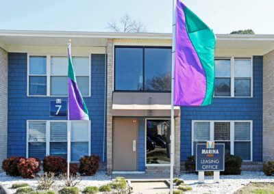 The front view of an apartment building adorned with vibrant purple and green flags, creating a lively atmosphere